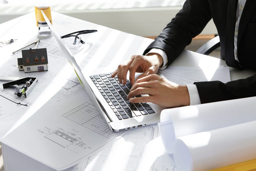hands-ceo-construction-company-black-suit-typing-message-via-e-mail-partners-laptop-with-drawings-seal-stamp-divider-table-2-scaled hands-ceo-construction-company-black-suit-typing-message-via-e-mail-partners-laptop-with-drawings-seal-stamp-divider-table-2-scaled